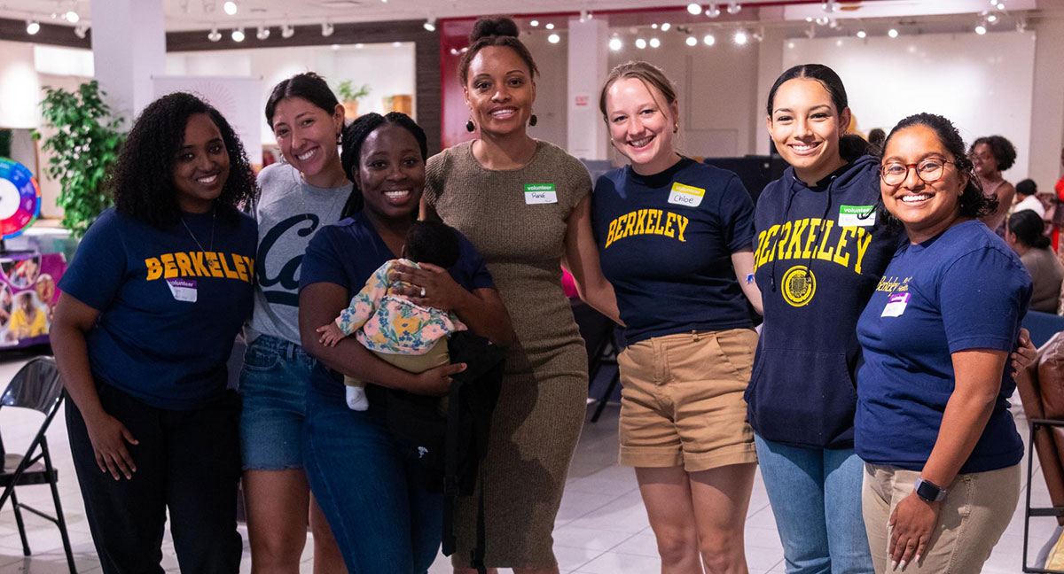 A group of people linking arms, many wearing UC Berkeley-branded apparel.