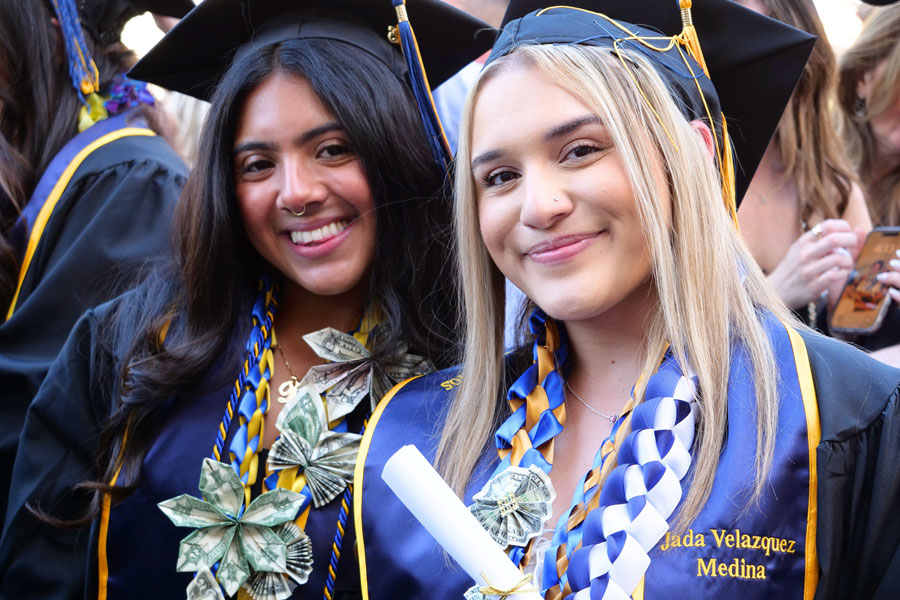 Two graduating students smile for a close-up photo at the graduation ceremony.