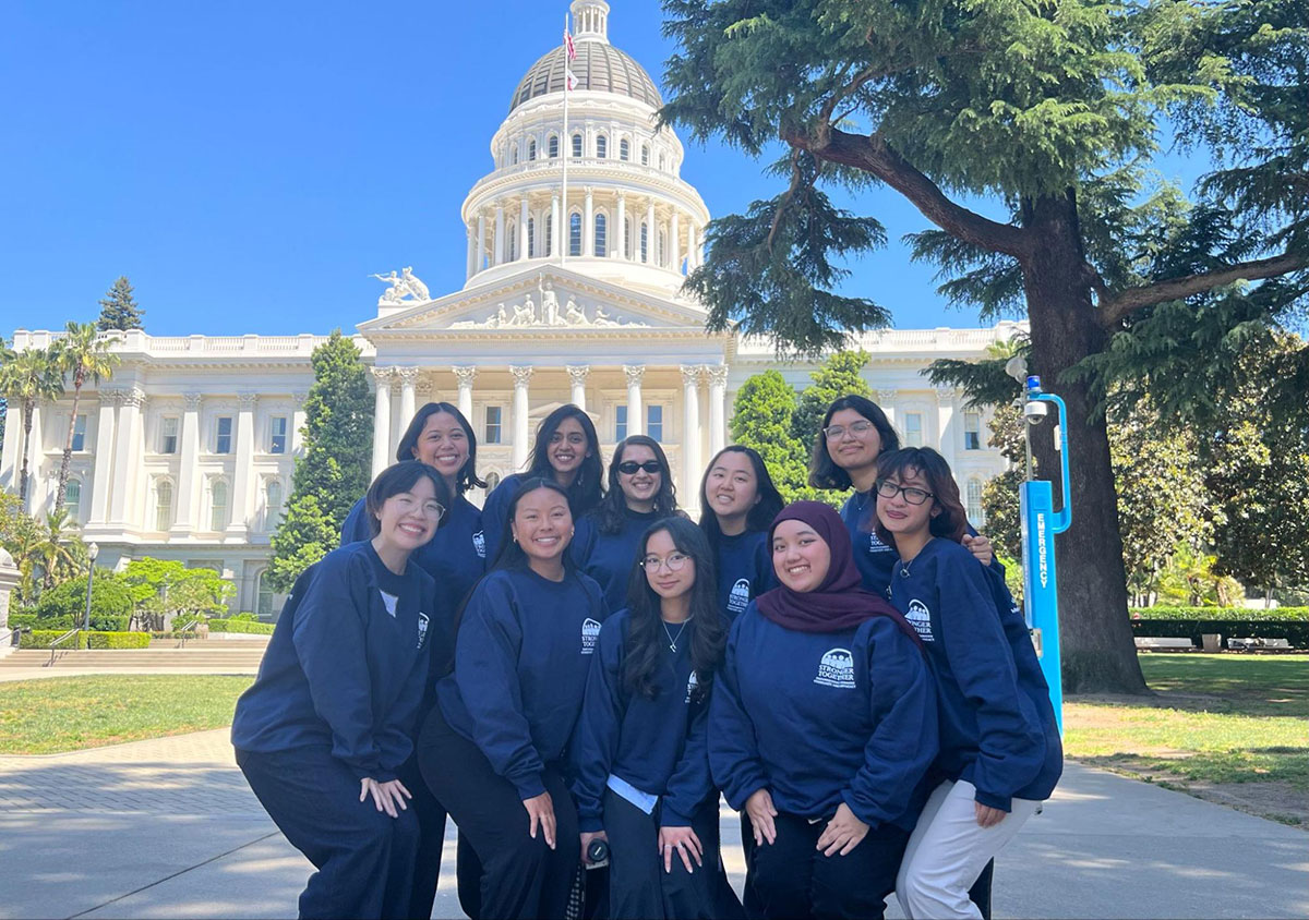 A group of program participants pose for a group photo in front of the California State Capitol building.