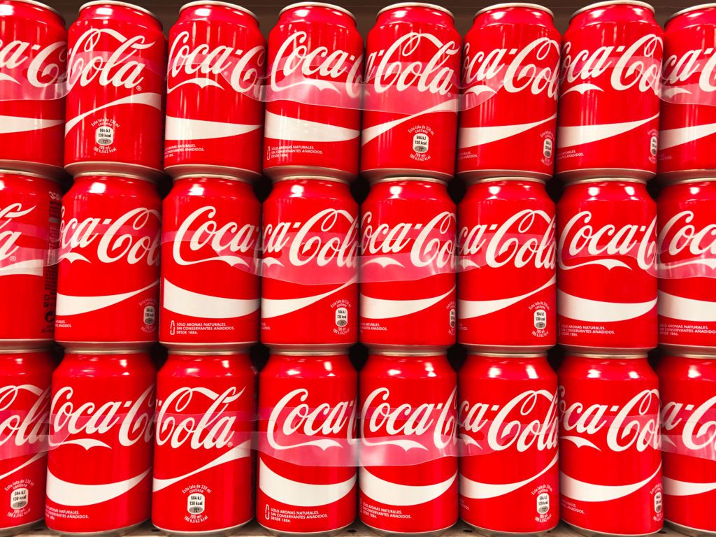 A large group of Coca-Cola red cans stacked in a supermarket