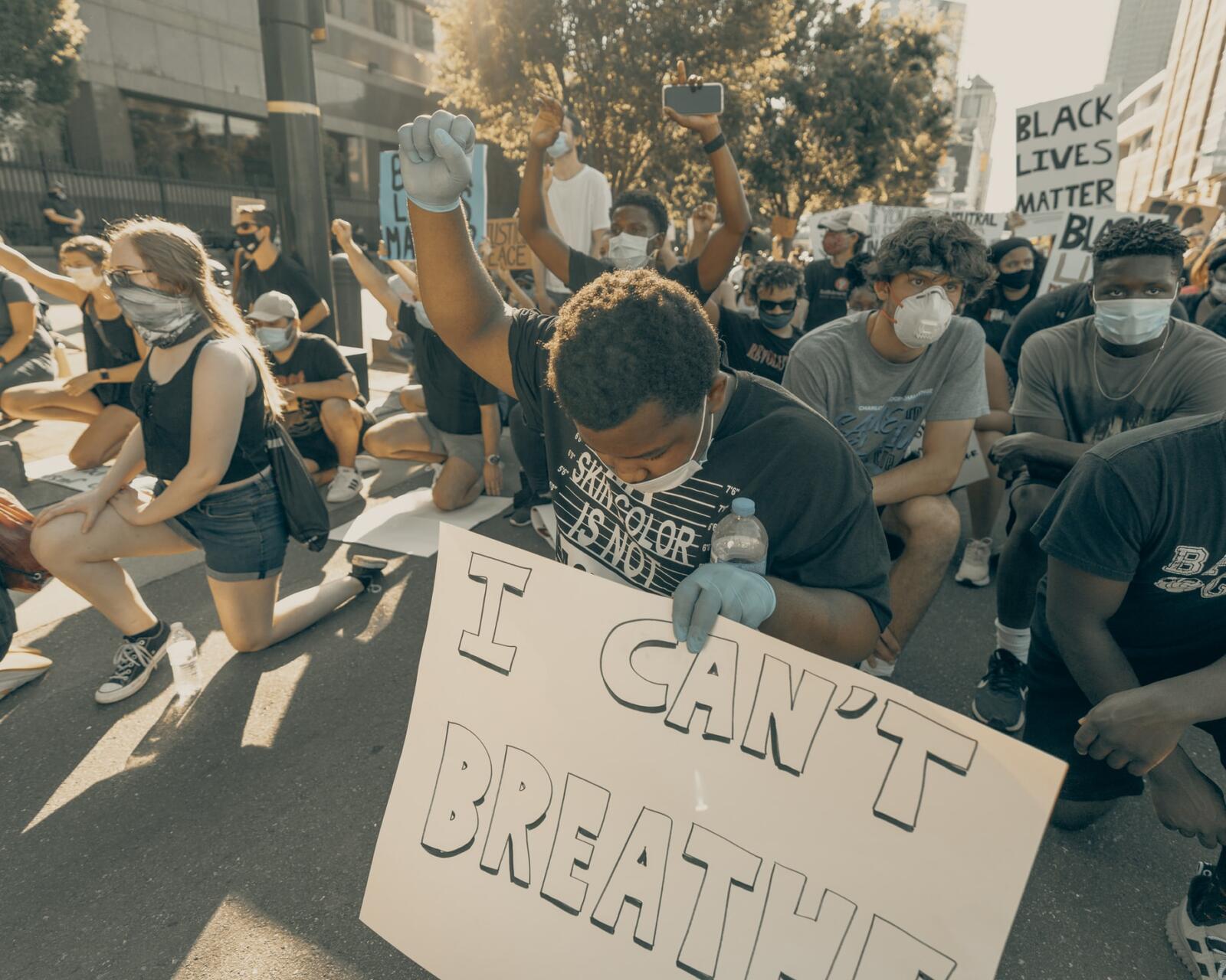 Protestor holding up his fist in solidarity in Charlotte, NC (Photo: Clay Banks via Unsplash)