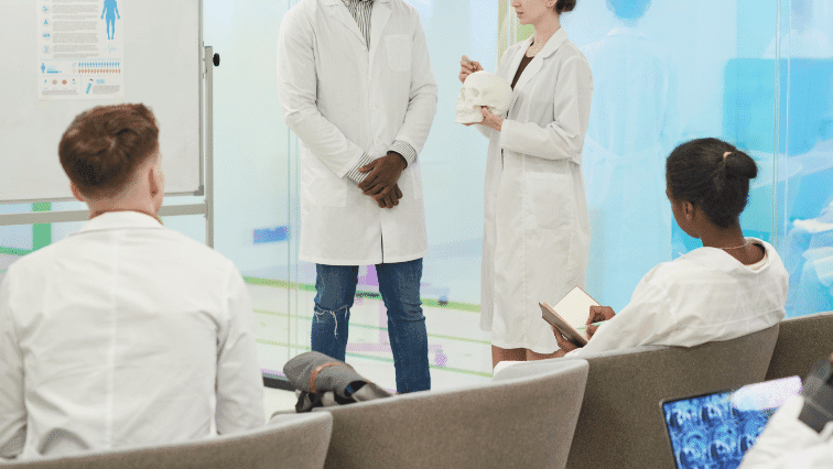 Medial practitioners wearing white coats and talking to each other in a medical setting.
