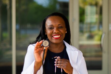 African American female doctor holding out stethoscope